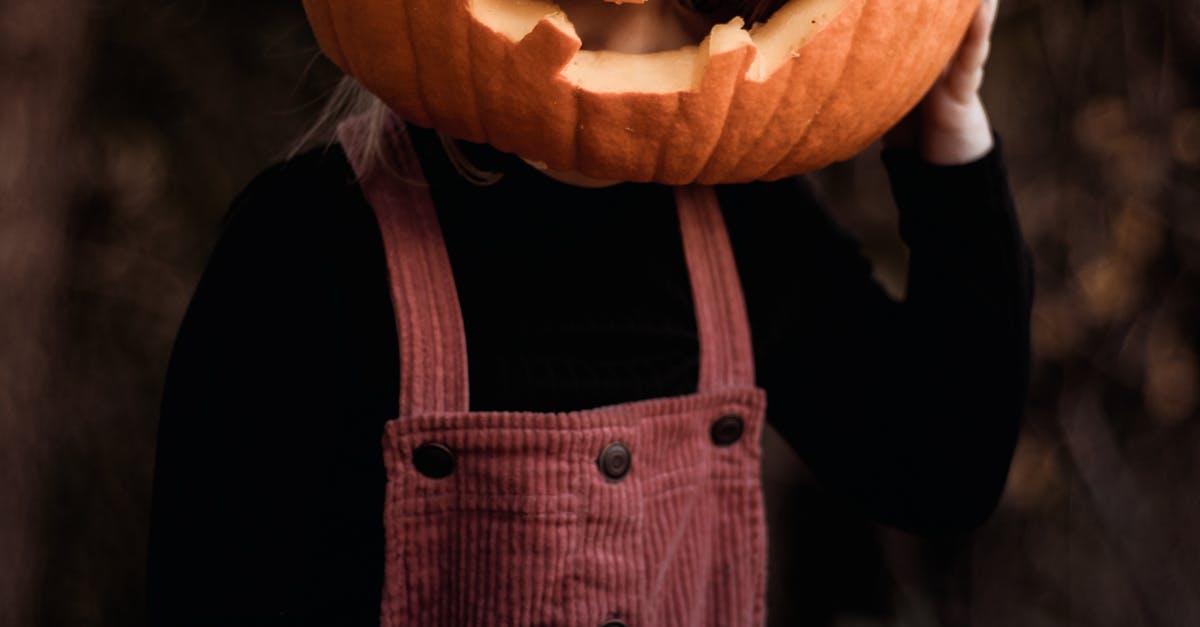 A child wearing a pumpkin on their head, celebrating Halloween outdoors in Smiths Falls, Canada.