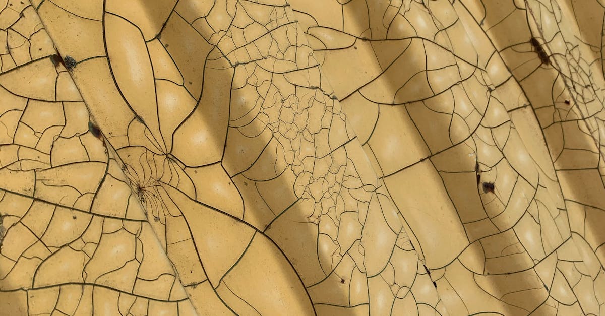From above of geometric yellow surface with symmetric patterns and cracks as abstract background