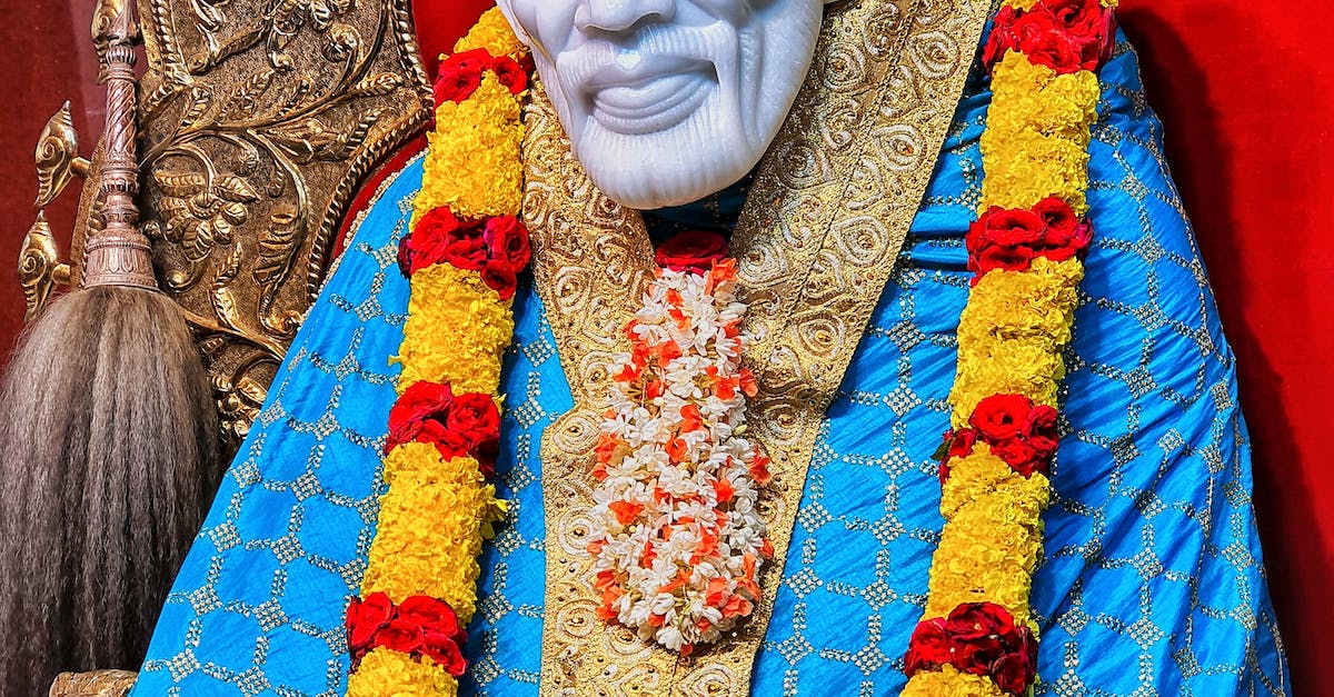 Sai Baba Statue Dressed in Bright Clothes Adorned with Flower Wreath