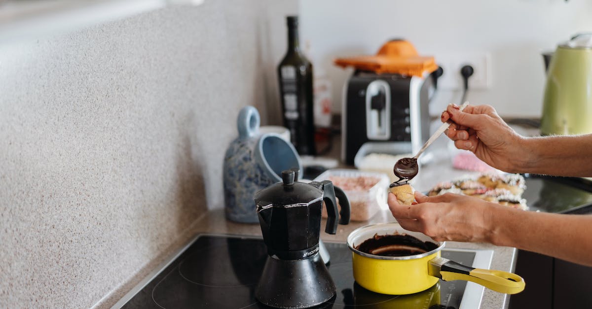 A woman is cooking in a kitchen with a coffee pot