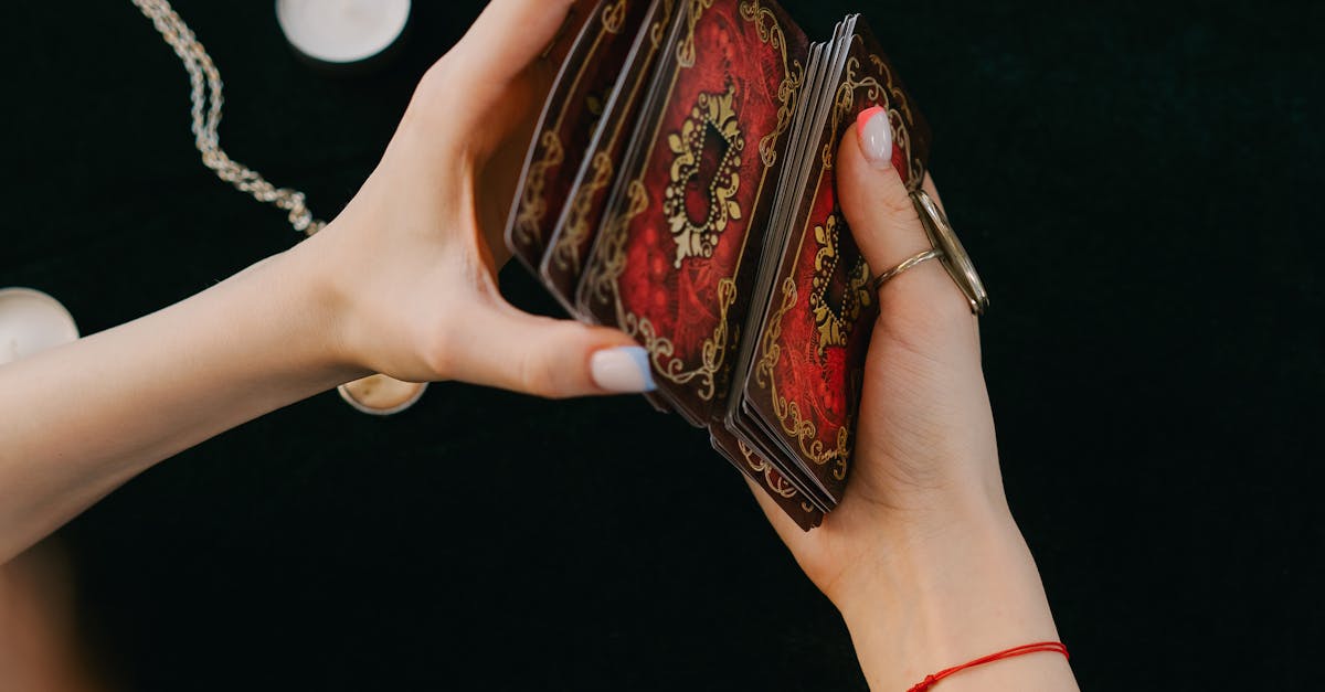 Anonymous female fortune teller shuffling tarot cards at table