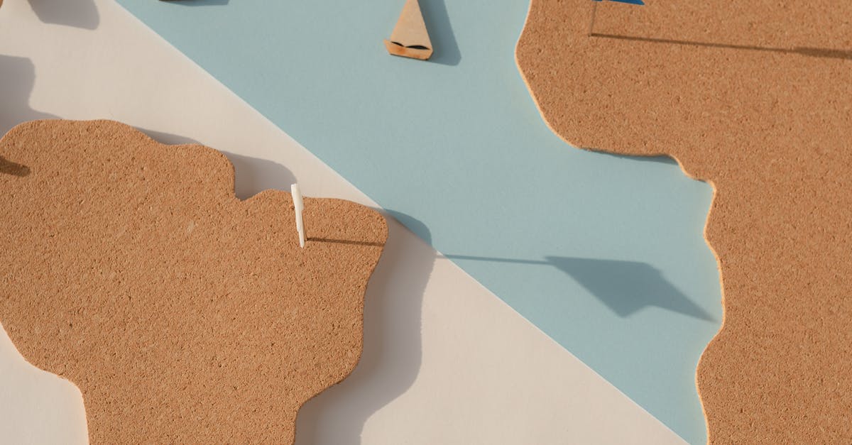 Cork cutout world map on pastel background with blue flags, ideal for geography and travel planning.