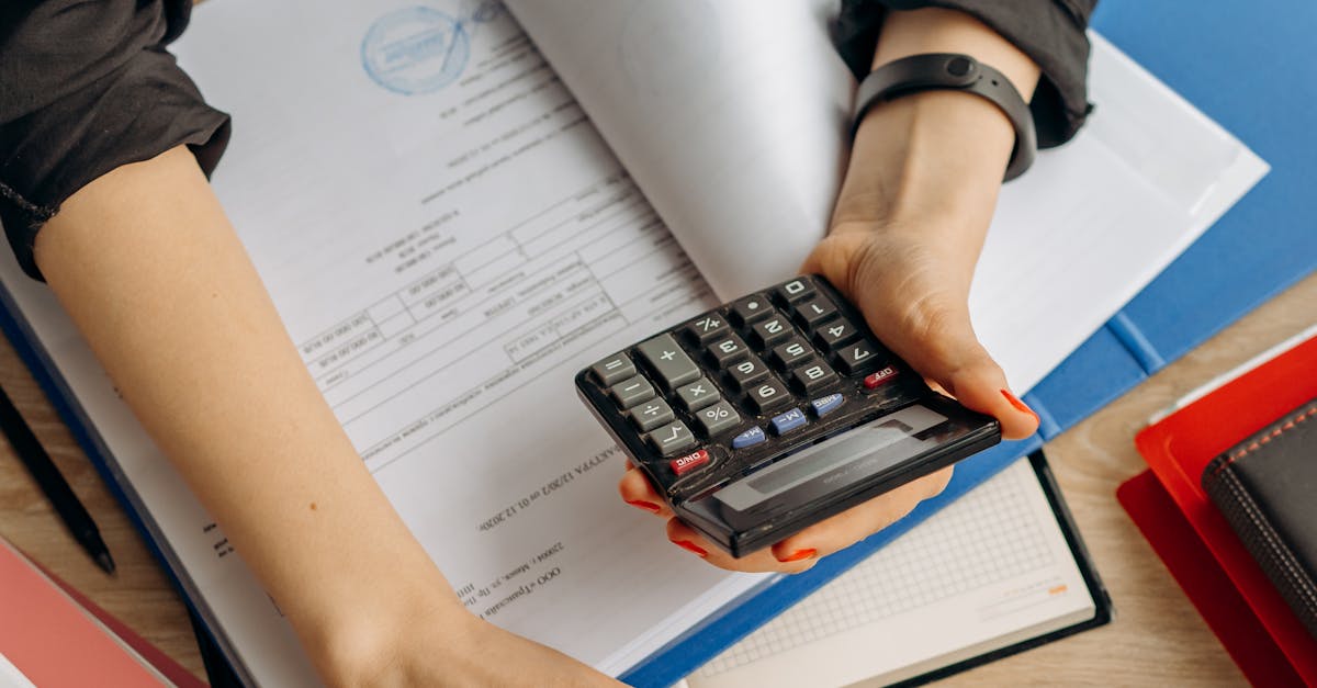 Person Holding Black Calculator While Using Laptop