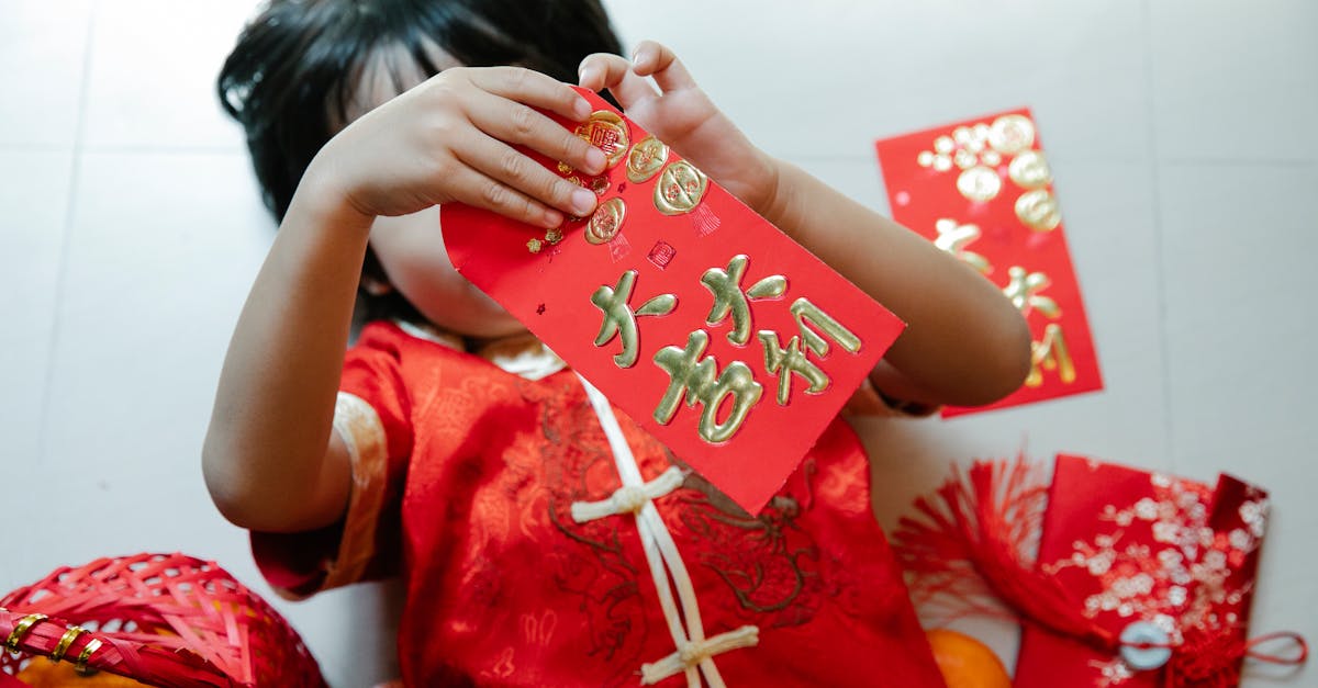 From above of anonymous child with red pocket lying on floor during festive occasion in house