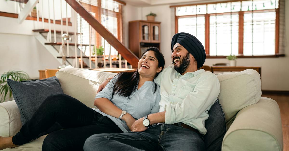 Laughing young Indian couple watching comedy movie together at home