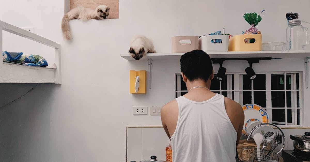 Man in White Tank Top Standing Near White Wall