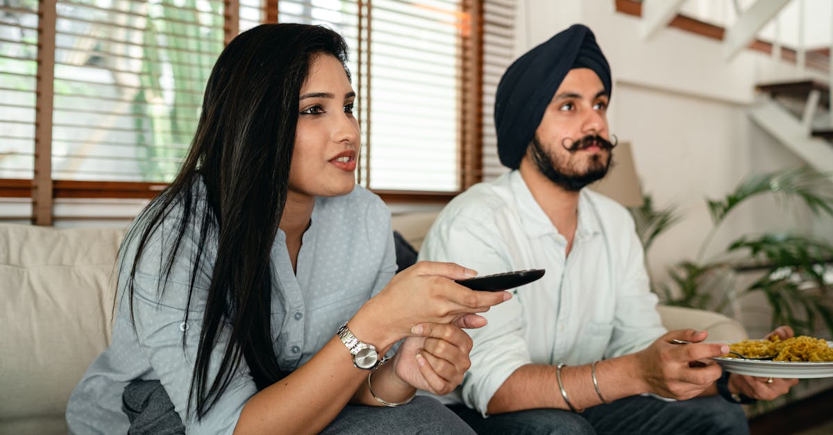 Serious ethnic couple watching movie on sofa