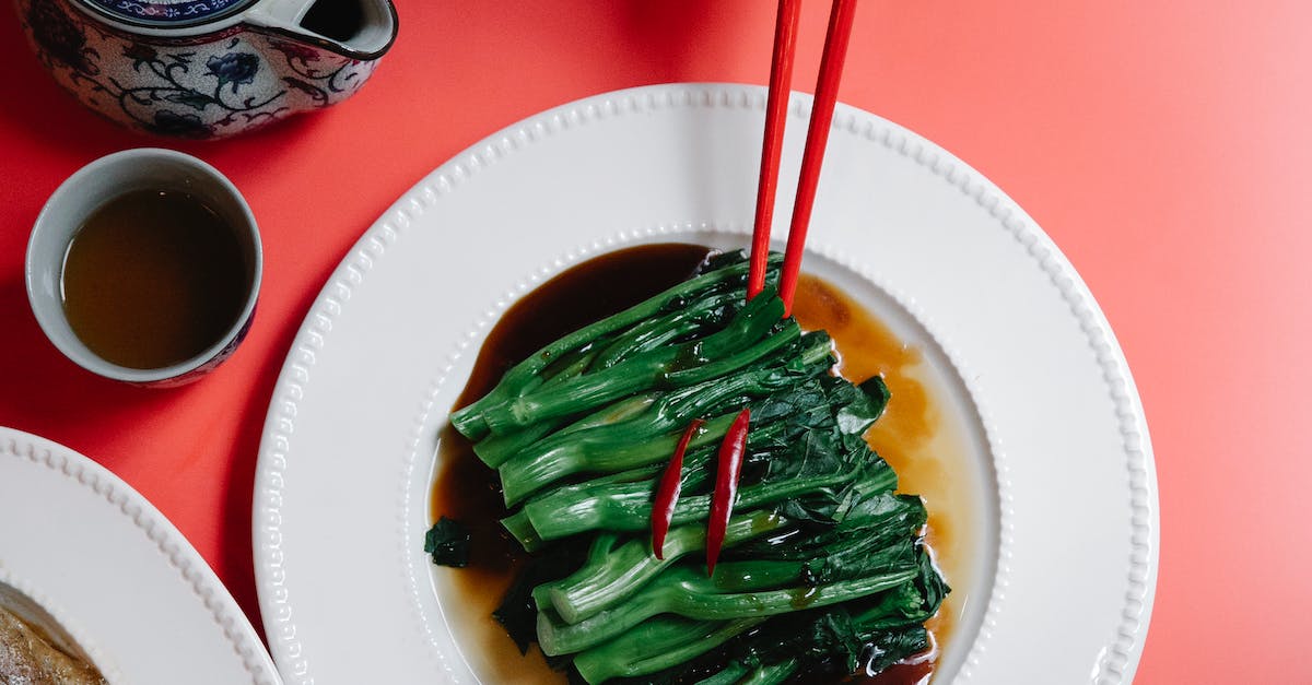 Crop woman with chopsticks above bok choy in soy sauce